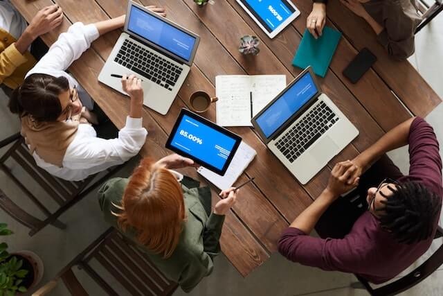 A group of coworkers sitting around a table while discussing a marketing report.